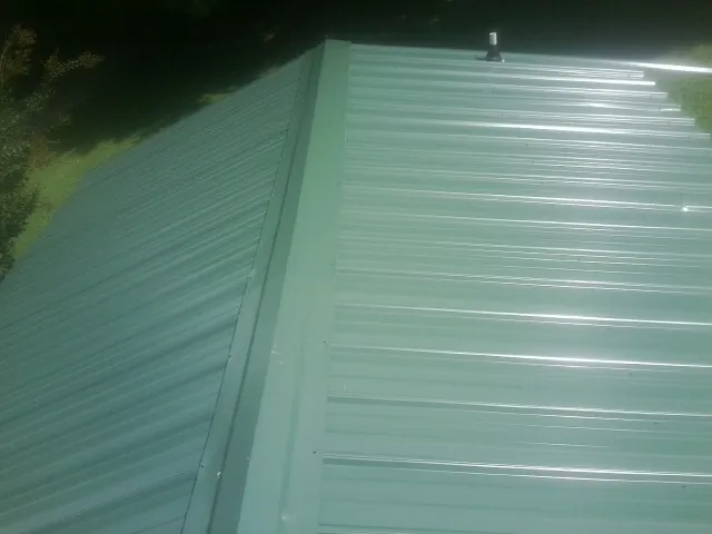 New green metal panels meeting at the ridge of a roof — Flat Roof Repair work by our crew in Ardara