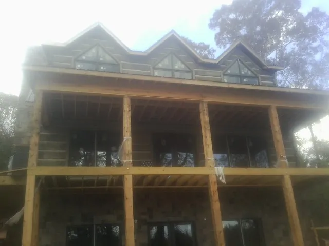 Dormers and porch framing on a large log home under construction — Roof Coating work by our crew in Ardara