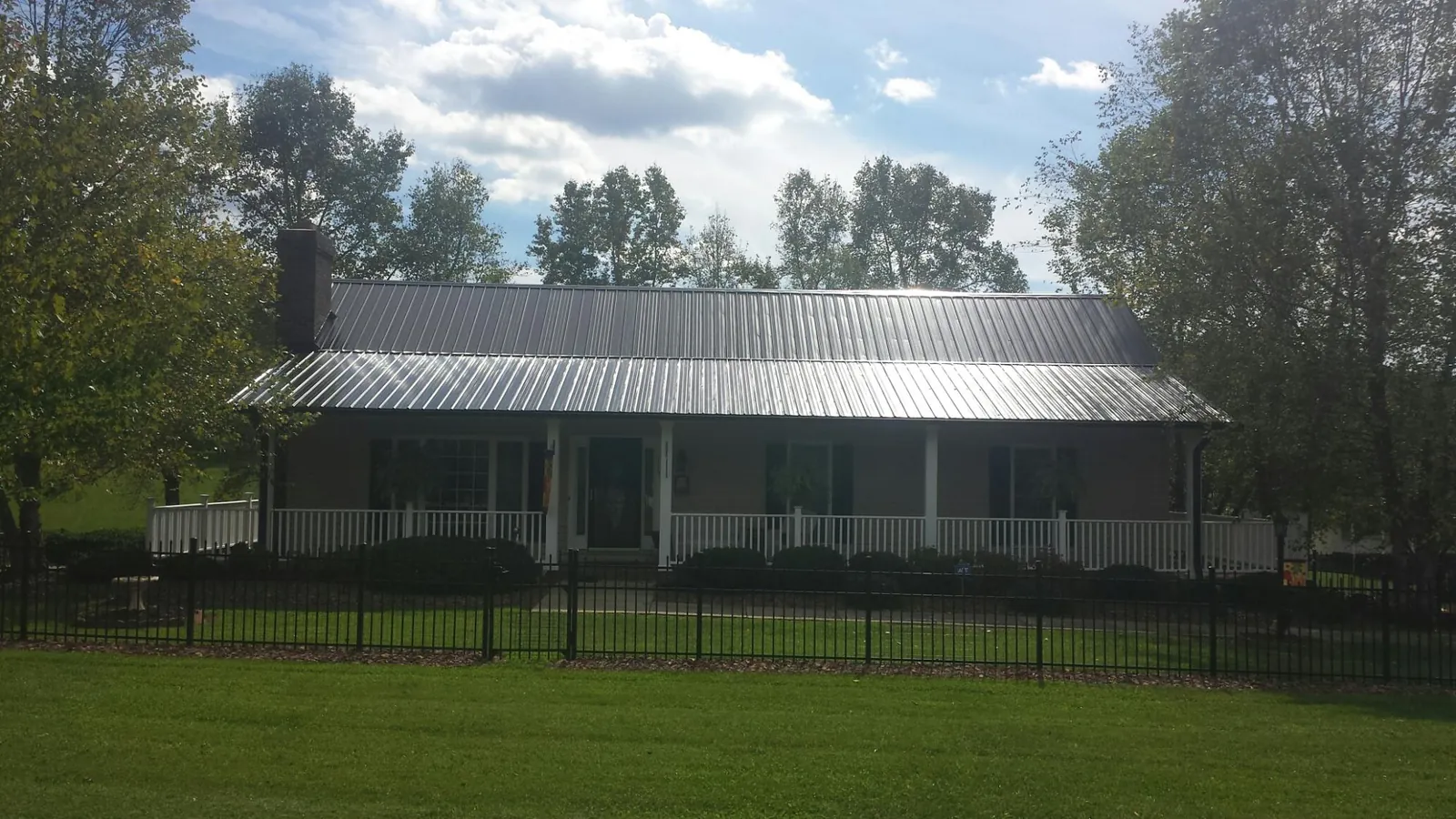Gray metal roof on a brick ranch with a full width front porch — Gutter Guard Installation work by our crew in Ardara