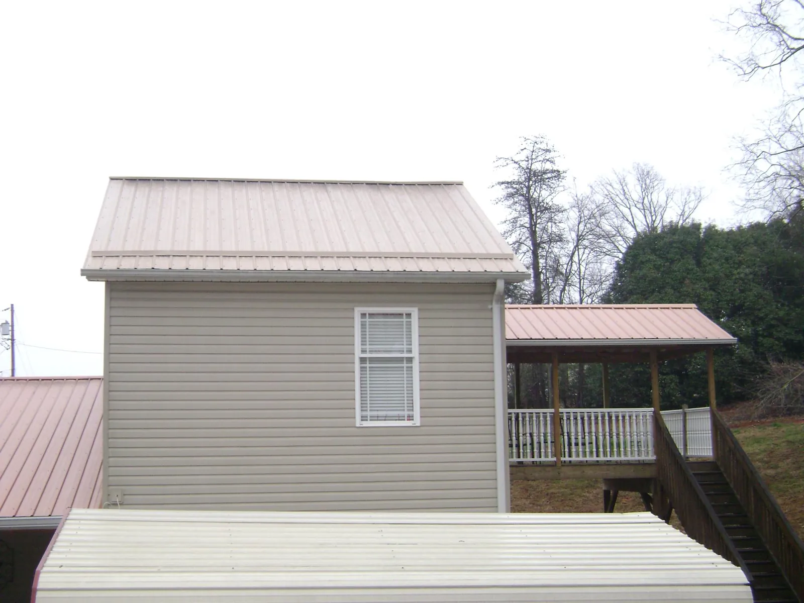 Tan metal roofs on a two story addition and attached porch, from a Roof Replacement job in Ardara