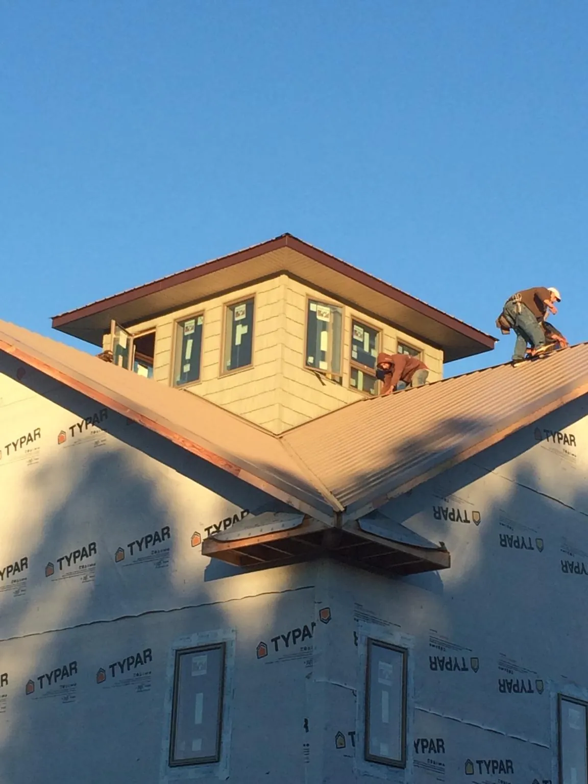 Roofers working around a rooftop cupola on a new metal roof at sunset — Roof Waterproofing in Ardara by Roofing Brothers